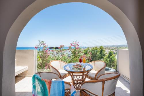 a table and chairs on a balcony with a view of the ocean at Aphea Village in Kolymvari