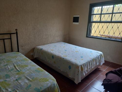 ein Schlafzimmer mit zwei Betten und einem Fenster in der Unterkunft Casa para temporada in Praia Grande