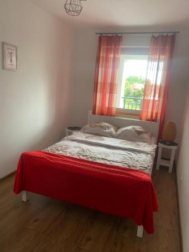 a bedroom with a bed with a red curtain and a window at APARTAMENT MARTA in Biłgoraj