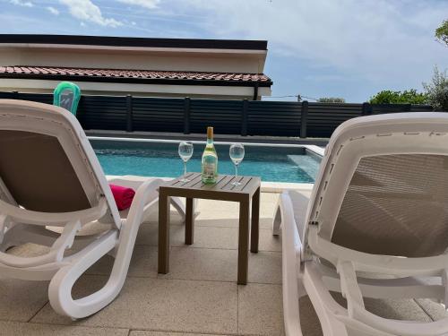 a table with two chairs and a bottle of wine at Apartman Dora in Šmrika