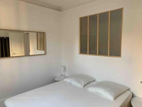une chambre blanche avec un lit et un miroir dans l'établissement Cosy 2 pièces 1 Chambre , 1 séjour, et 1 coin bureau, à Boulogne-Billancourt