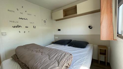 - une chambre avec 2 lits et un bureau sur le mur dans l'établissement Mobilhome Eleganzia - Cc921 Les Charmettes 4 stars, aux Mathes