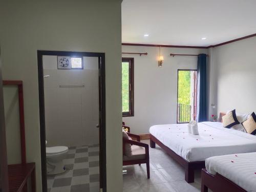 a bedroom with a bed and a bathroom with a toilet at Dok Champa Resort in Vang Vieng