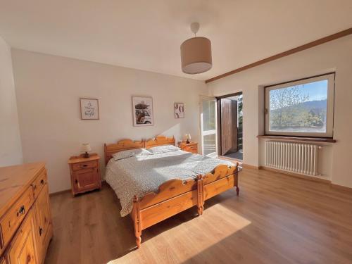 a bedroom with a wooden bed and a large window at Mountain Chalet Tre Marie in Cavalese