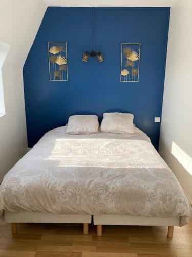 une chambre avec un mur bleu et un lit dans l'établissement Charmant 2 pièces à Cabourg - 80 m de la plage, à Cabourg