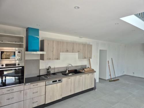 une cuisine avec des armoires en bois et un four à plaques de cuisson dans l'établissement Gites du havre de la venlee, à La Celle-sous-Gouzon