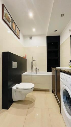 a bathroom with a toilet and a sink and a washing machine at Apartament w Centrum in Przemyśl