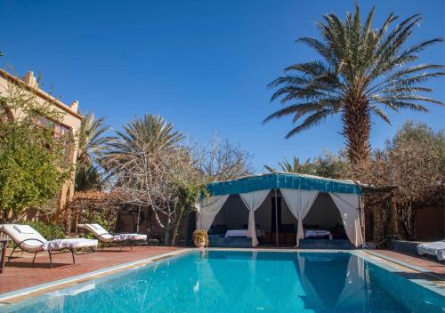 a swimming pool with a tent and palm trees at Bassatine Skoura in Skoura