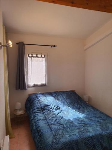 une chambre avec un lit bleu et une fenêtre dans l'établissement Maison climatisée 2 chambres idéalement située Narbonne plage, à Narbonne-Plage