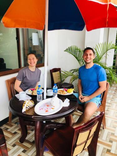 two men sitting at a table with an umbrella at Holiday Villa in Trincomalee