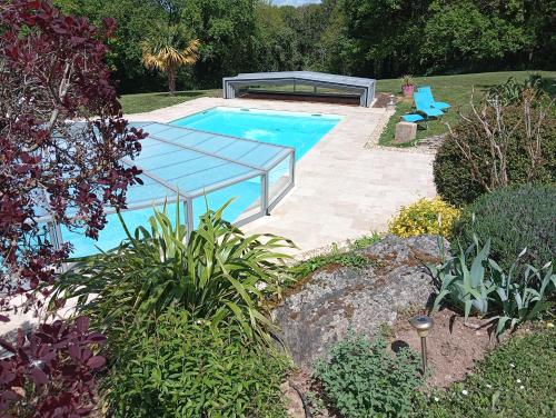 une piscine avec une table en verre dans un jardin dans l'établissement Le POULAILLER, à Mareuil-sur-Lay