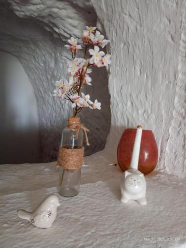 a vase with flowers in it next to a candle and an apple at Maison troglodytique au coeur des Châteaux de la Loire - Le Cerisier Perché in Luynes