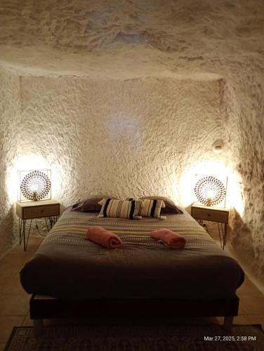 a bedroom with a bed in a stone wall at Maison troglodytique au coeur des Châteaux de la Loire - Le Cerisier Perché in Luynes