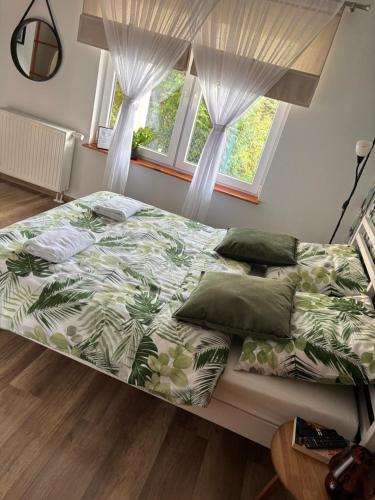 a bed in a bedroom with two windows at Dom Na Wzgórzu in Poręba