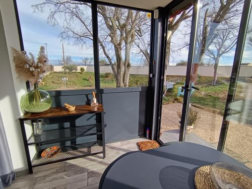 Cette chambre dispose d'une porte en verre avec une table et une fenêtre. dans l'établissement Les Garrigues de l'Oluké - Spa privatif, Piscine, Tennis, à Piolenc