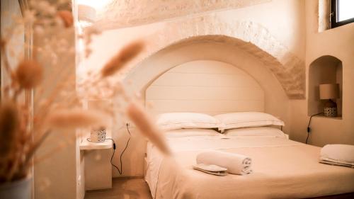 a bedroom with a white bed with an arched wall at Masseria Surace in Noci