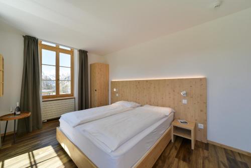 a bedroom with a bed and a large window at Hotel Maloja Kulm in Maloja