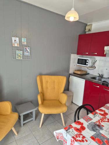 une cuisine avec des armoires rouges et une table et des chaises dans l'établissement Magnolia, à Perros-Guirec