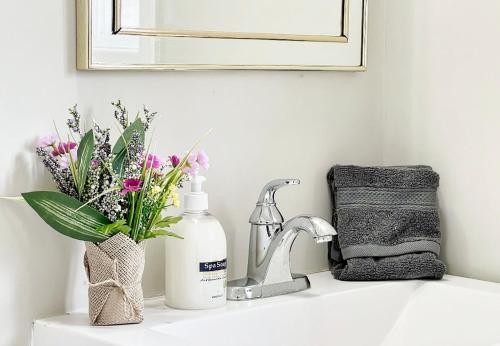 a bathroom sink with flowers and a mirror at ROOM NEXT TO CANADA WONDERLAND-10 mins Drive- FREE PARKING-WIFI in Vaughan