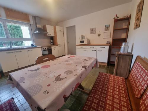 une cuisine avec une table et un tissu de table fleuri dans l'établissement les balcons de Fellering, à Fellering