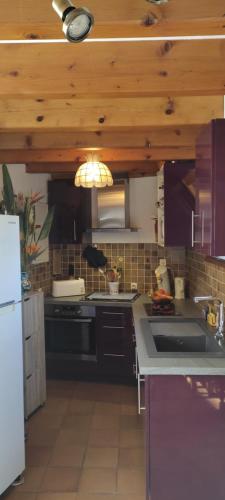 - une cuisine avec des appareils noirs et un plafond en bois dans l'établissement presqu'il de st Mandrier sur mer var location saisonnières, à Saint-Mandrier-sur-Mer