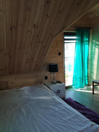 a bedroom with a bed in a room with wooden ceilings at Bajkowa Chatka in Bodzentyn