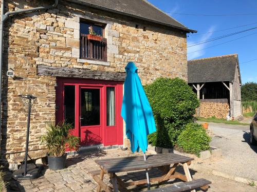 un parapluie bleu assis sur une table devant un bâtiment dans l'établissement Les Moineaux, à Val Couesnon