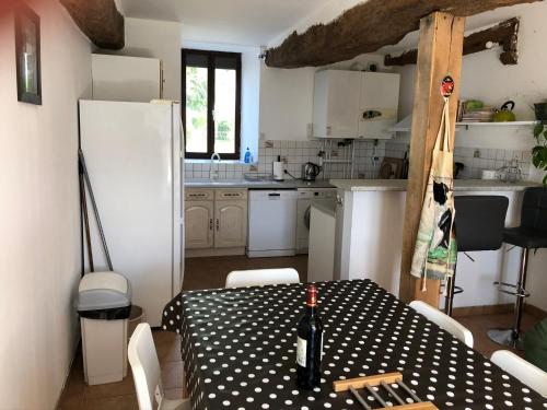 une cuisine avec une table et un réfrigérateur blanc dans l'établissement Les Moineaux, à Val Couesnon