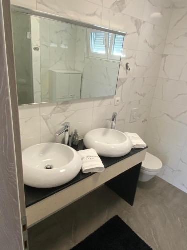 a bathroom with two sinks and a mirror and a toilet at Villa Fidelissima in Kaštela
