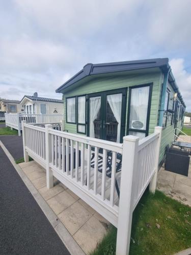 a green mobile home with a white fence at Private Caravan to Hire - Marton Mere Haven Holiday Village in Blackpool