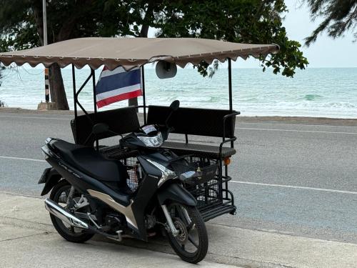 a motorcycle parked under an umbrella on the side of the road at sea sand sun resort Executive 607 Mae Rumphueng beach in Rayong