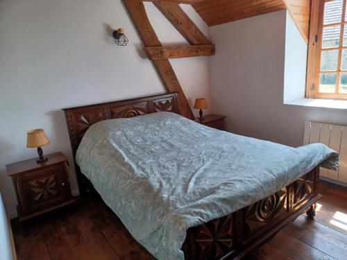 a bedroom with a bed with a green comforter and a window at Gîtes du breuil in Clugnat