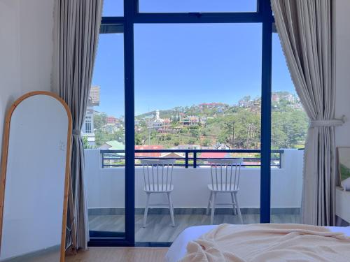a bedroom with a view of a balcony with two chairs at Lux Nest Villa Đà Lạt in Da Lat