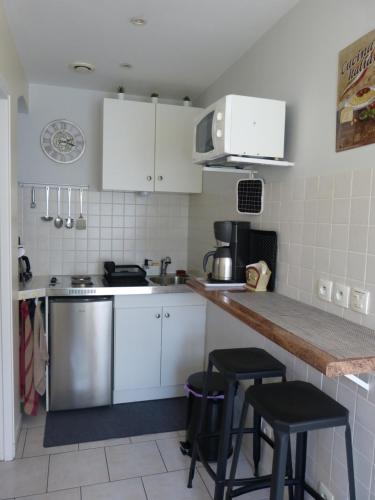 une cuisine avec des armoires blanches et un comptoir avec des tabourets dans l'établissement Appartement Elody - Villa Cocooning, à Houilles