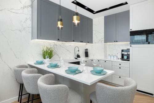 a white kitchen with a white table and chairs at Sea View Baltic Lux Hevenia in Rewal