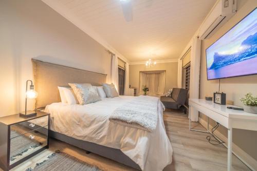 a bedroom with a bed and a flat screen tv at Room 4 - LEO Sky Guest House in Simondium