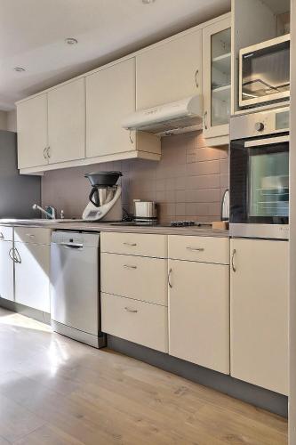 une cuisine avec des armoires blanches et des appareils électroménagers blancs dans l'établissement Superbe 3 ch avec ascenseur parking hyper centre Trouville, à Trouville-sur-Mer