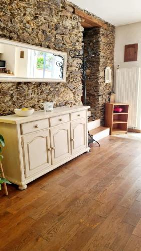 - une cuisine avec des placards blancs et un mur en pierre dans l'établissement Pierre et rivière - Une terrasse en ville, à Nantes
