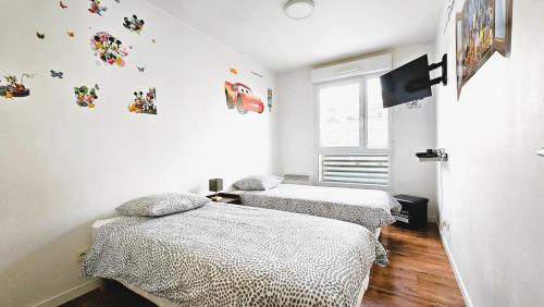 deux lits jumeaux dans une chambre aux murs blancs dans l'établissement Appartement Confort Paris, à Montévrain