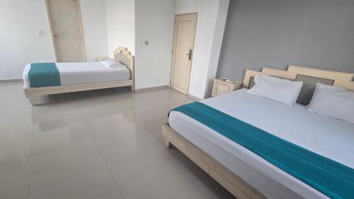 a bedroom with two beds and a tiled floor at Hotel Med Barranquilla Centro in Barranquilla
