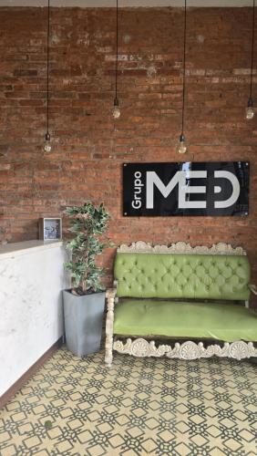 a green bench against a brick wall with a sign at Hotel Med Barranquilla Centro in Barranquilla