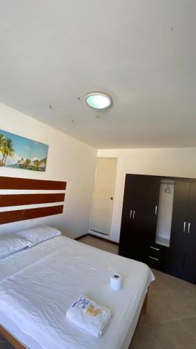 a bedroom with a white bed with a red stripe on it at Hospedaje Rio Hotels Mancora in Máncora