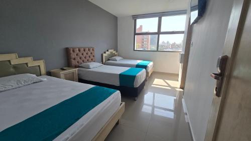 a hotel room with two beds and a window at Hotel Med Barranquilla Centro in Barranquilla