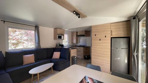 un salon avec un canapé bleu et une cuisine dans l'établissement Mobile home in the Bay of Bonne Anse Plage La Palmyre, aux Mathes