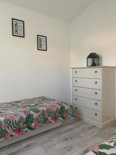 a bedroom with a dresser and a bed with a bedspread at Pachnący Jaśmin in Zwierzyniec