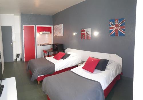 a hotel room with two beds with red pillows at L'ANNEXE Résidence Hôtelière classée in Pontivy