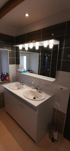 une salle de bain avec deux lavabos et un grand miroir dans l'établissement Le Coquelicot, à Pléven