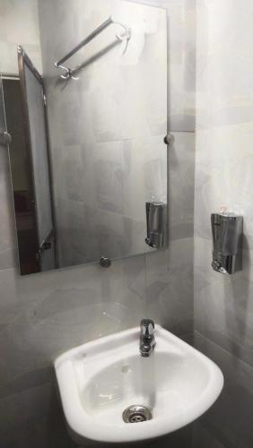 Un lavabo blanco en un baño con espejo. en The Malshej Mist, en Ghātghar