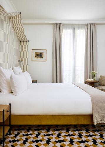 a large white bed in a room with windows at Hôtel Noucha in Paris