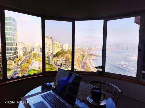 a laptop sitting on a table with a view of the ocean at Oceanfront Miraflores Larcomar next to Marriott in Lima